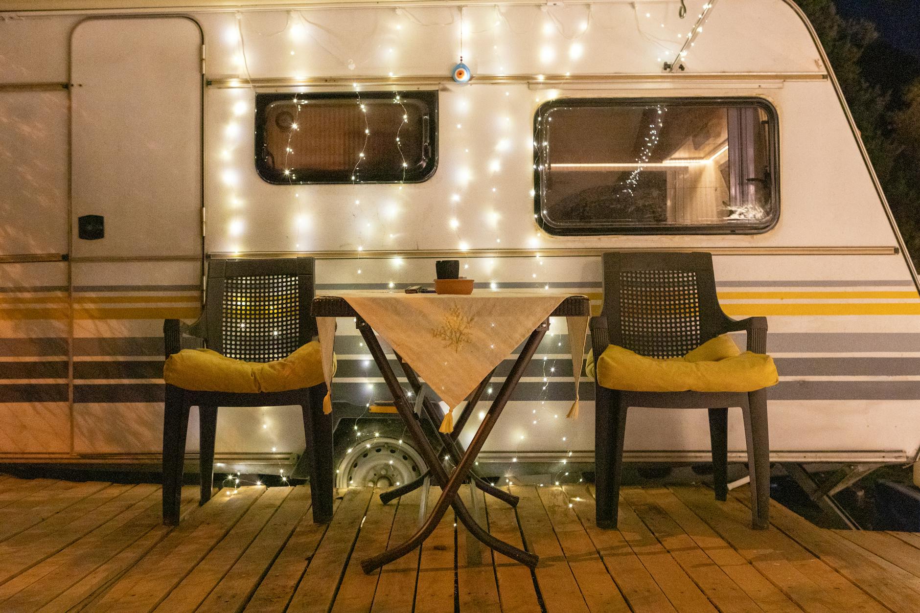 Zona exterior con mesa y sillas junto a una caravana